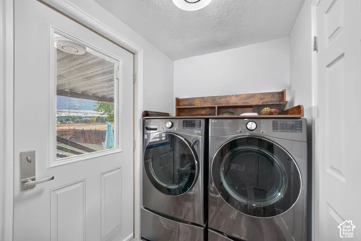 Laundry area with stacked appliances, durable door, and overhead lighting