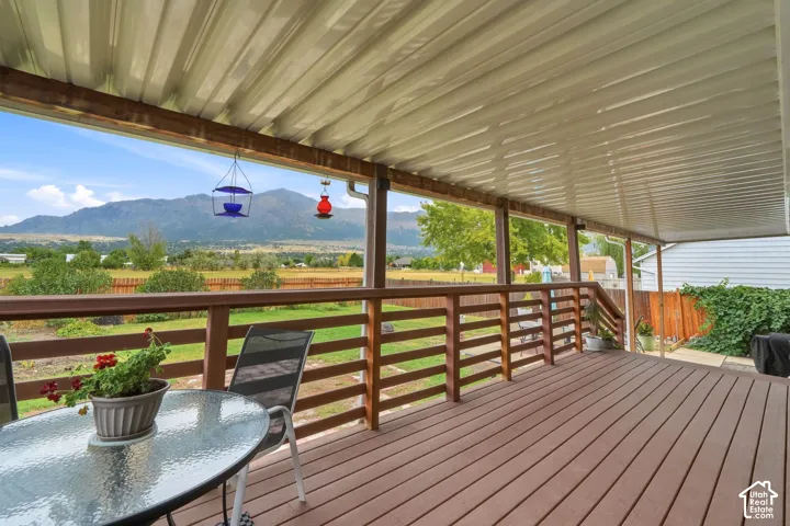 Expansive covered deck with wood-finish flooring and a mountain backdrop