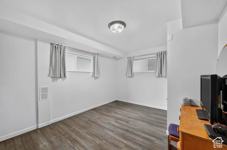 Wood-finish flooring, white walls, and a flush-mount ceiling light