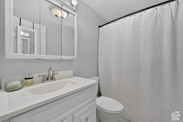 White vanity with integrated sink, brushed nickel faucet, wall-mounted mirrored medicine cabinet, and overhead vanity lighting