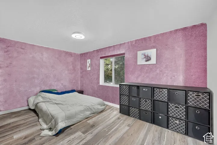 Wood-finish flooring, purple textured walls, flush-mount ceiling light, and a window for natural light