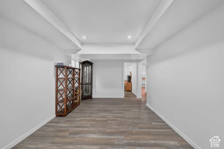 Wood-finish flooring with white baseboards, recessed lighting, and white walls