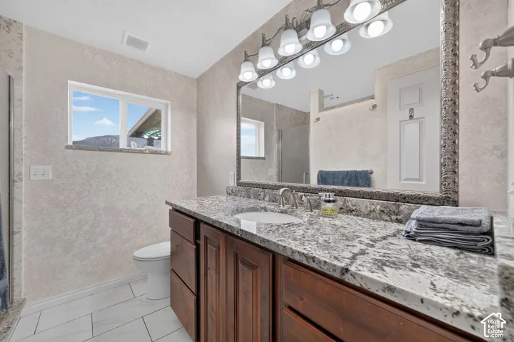 Vanity with a light-toned countertop, wood-finish cabinetry, and an undermount sink