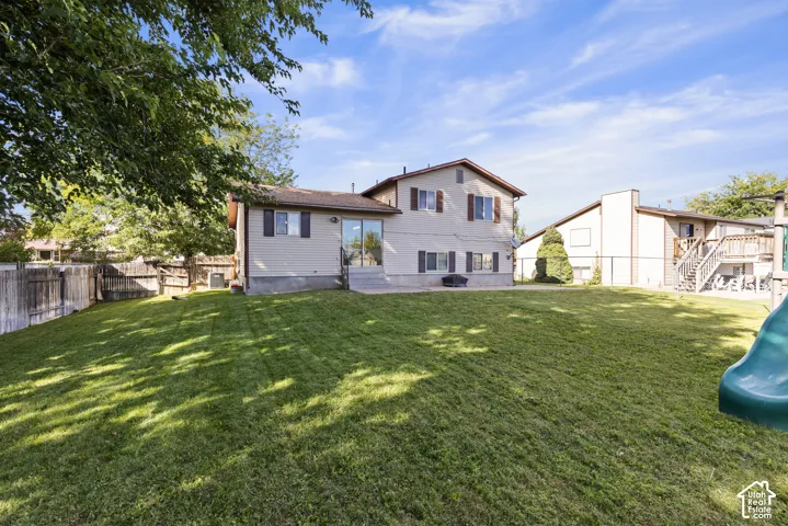 Expansive lawn area with a two-story residence featuring siding and shutter accents, a lower-level sliding glass door, and an upper-level window