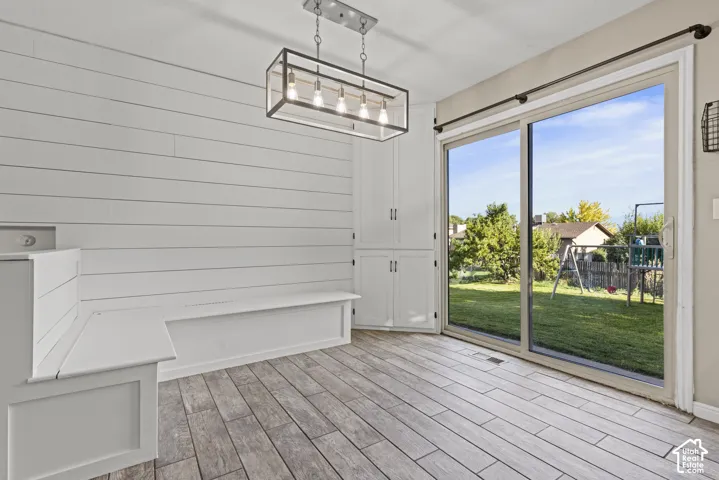 Built-in seating with shiplap wall, wood-finish flooring, sliding glass door, and built-in cabinetry
