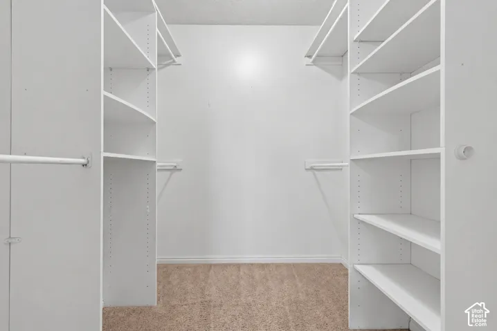 Built-in closet system featuring multiple shelves and hanging rods, neutral wall color, and carpeted flooring