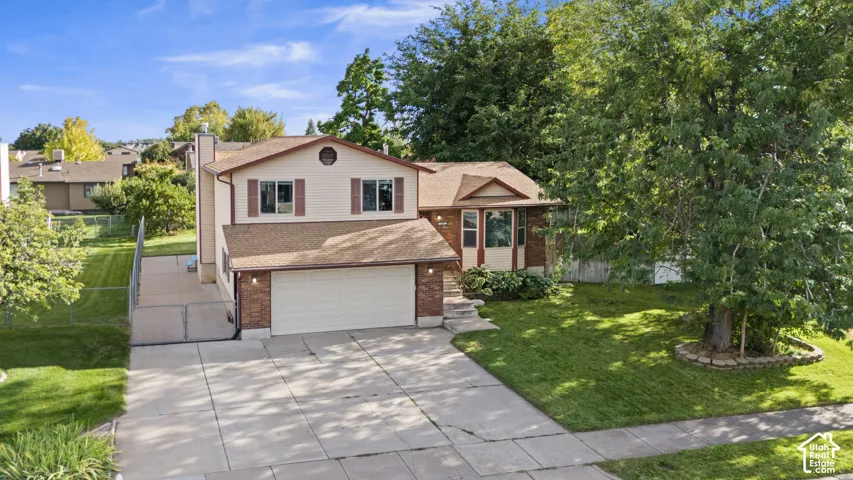 Two-story residence featuring a brick facade, attached two-car garage, established front landscaping, and a concrete driveway