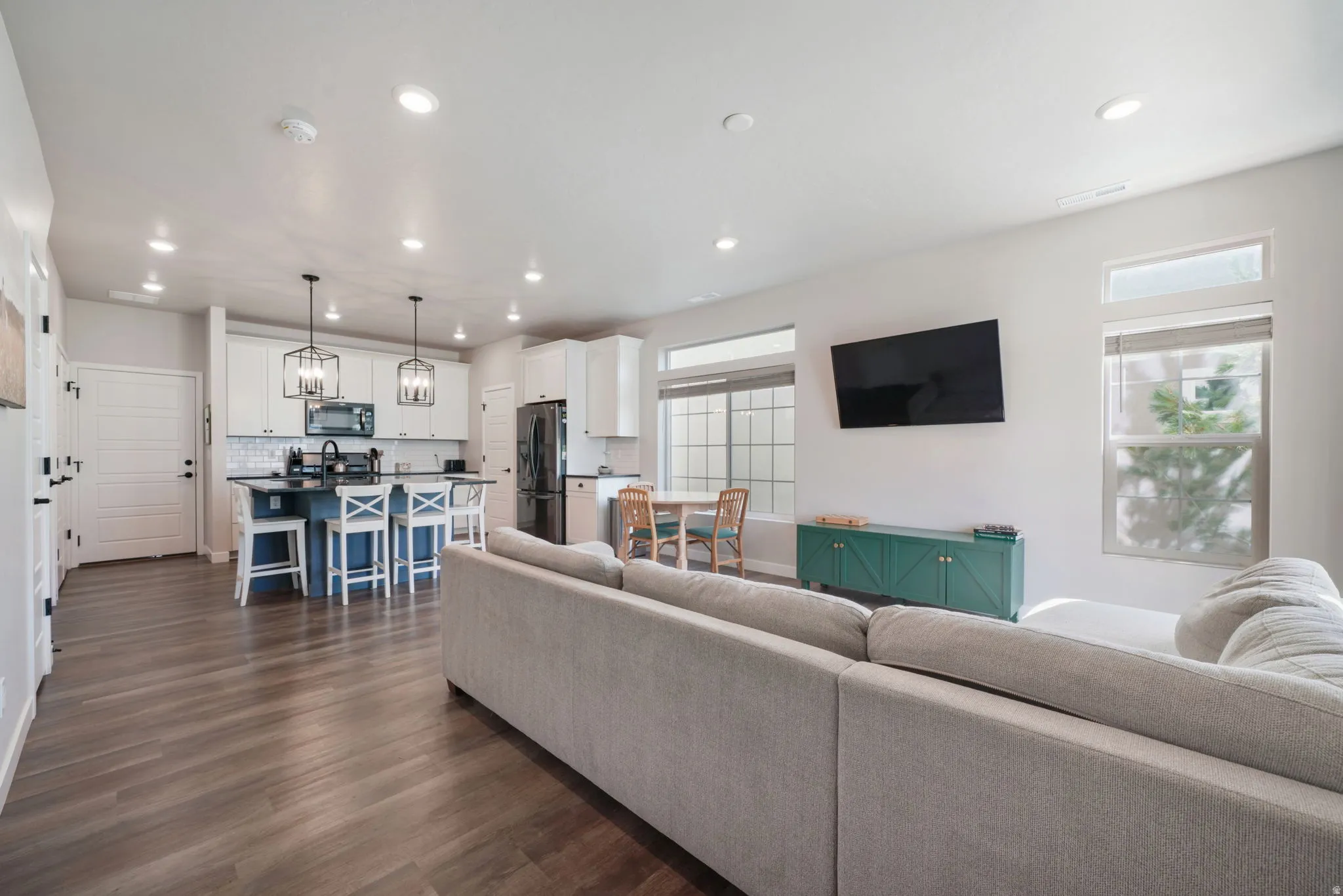 Open-concept living space with wood-finish flooring, recessed lighting, and kitchen island with pendant fixtures