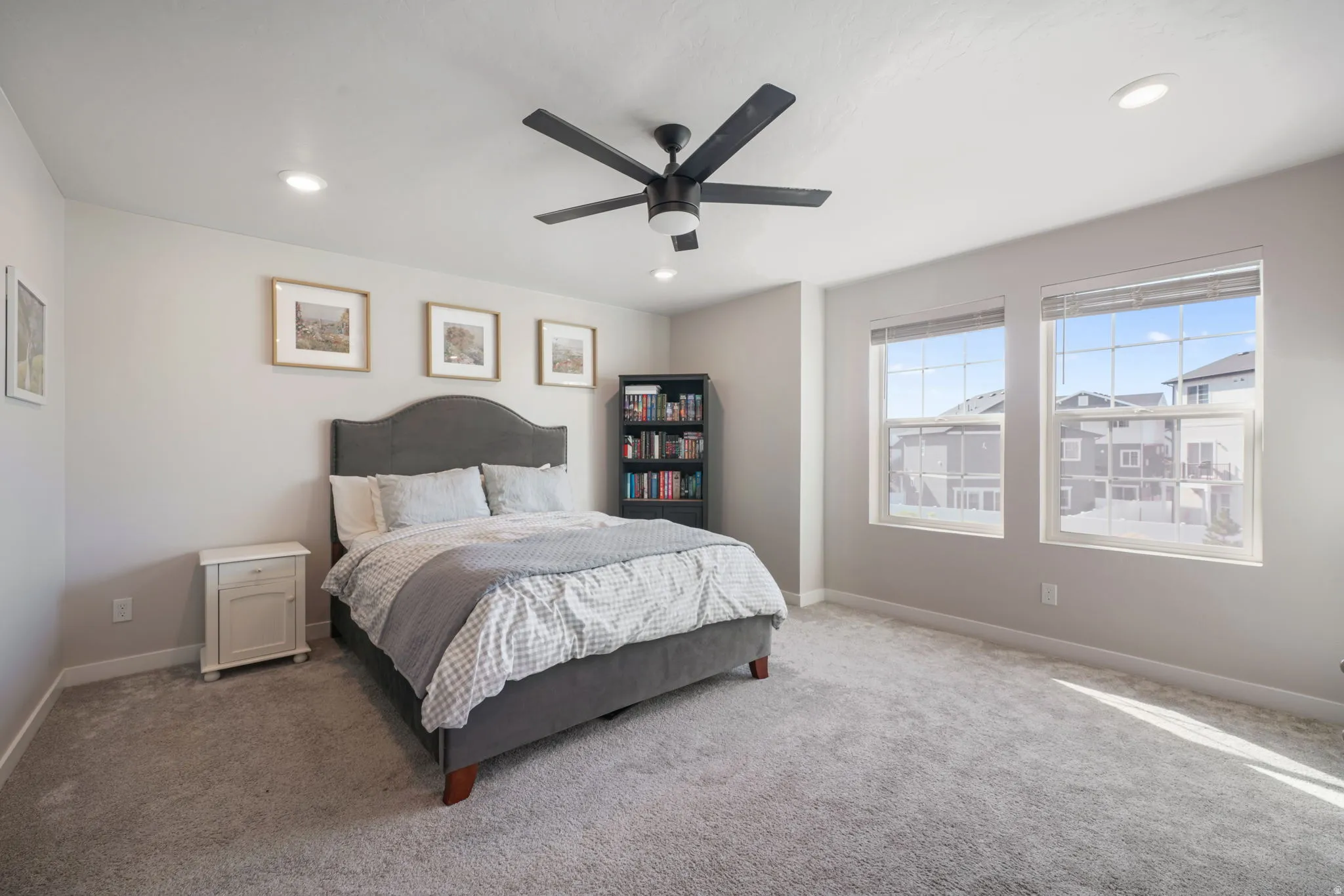 Recessed lighting, ceiling fan, two windows, and light gray carpeting