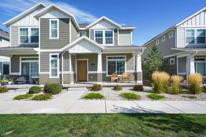 Two-story residence featuring a covered entry, siding exterior, and a manicured front lawn with mature landscaping