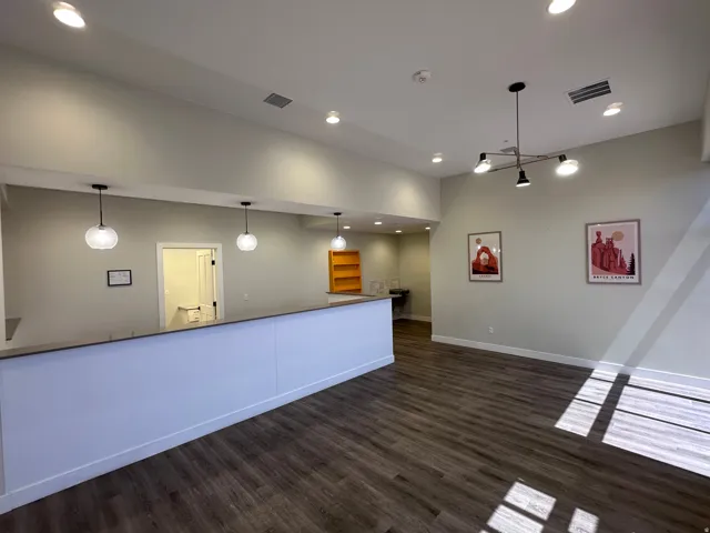 Recessed lighting, wood-finish flooring, and multiple pendant lights illuminate this open space