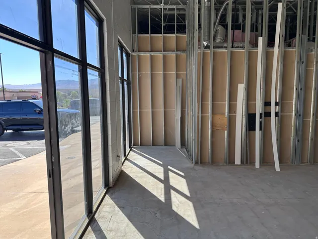 Black-framed storefront windows, polished concrete flooring, metal stud framing, and partial drywall