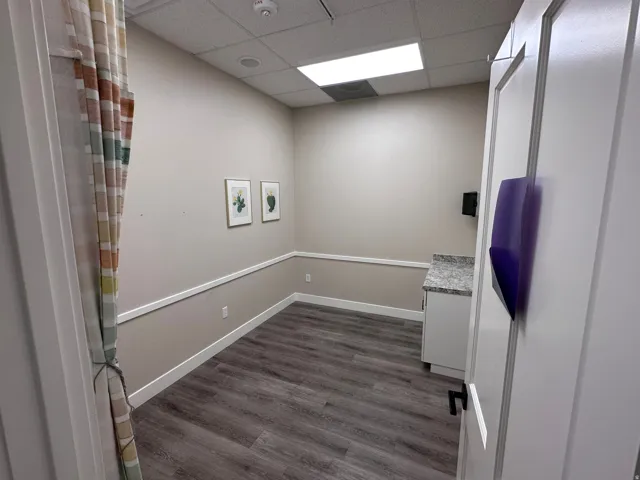 Wood-finish flooring, white wall paneling, and a white vanity with a speckled countertop
