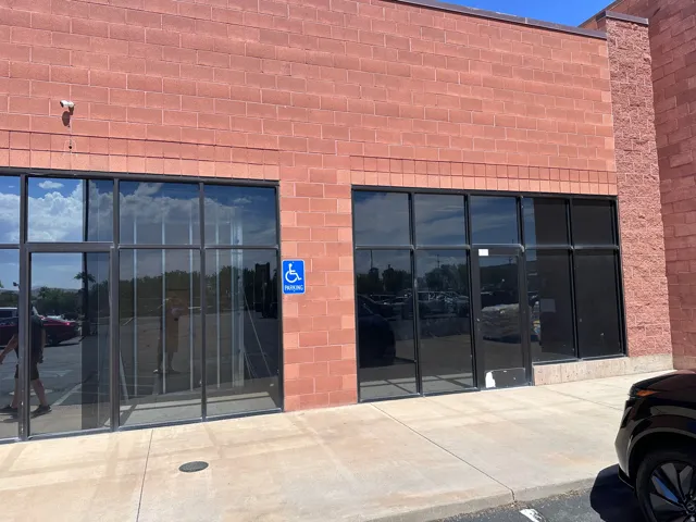 Brick exterior with multiple large storefront windows and a concrete sidewalk