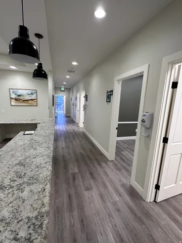 Wood-finish flooring throughout, featuring a long hallway with multiple doorways
