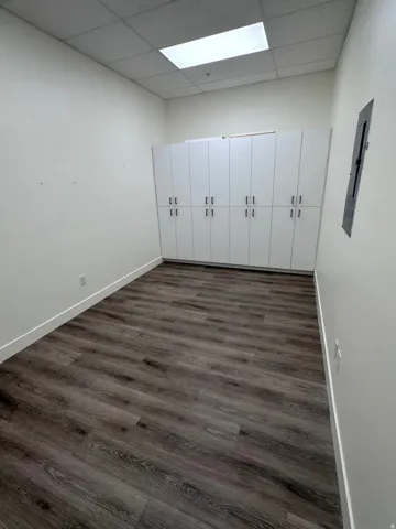 Wall-to-wall built-in cabinetry with matte black hardware, wood-finish flooring, and recessed ceiling lighting