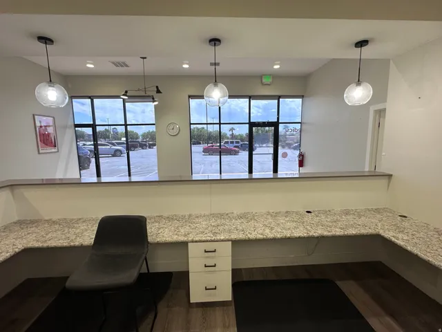 Expansive window line providing natural illumination, L-shaped countertop with integrated storage, wood-finish flooring, and contemporary pendant lighting
