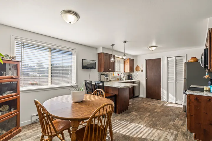 Wood-finish flooring, white walls, and a large window with blinds