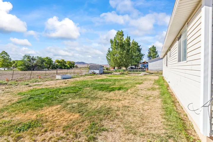 Expansive lot featuring a storage shed and perimeter fencing, with mountain scenery in the background