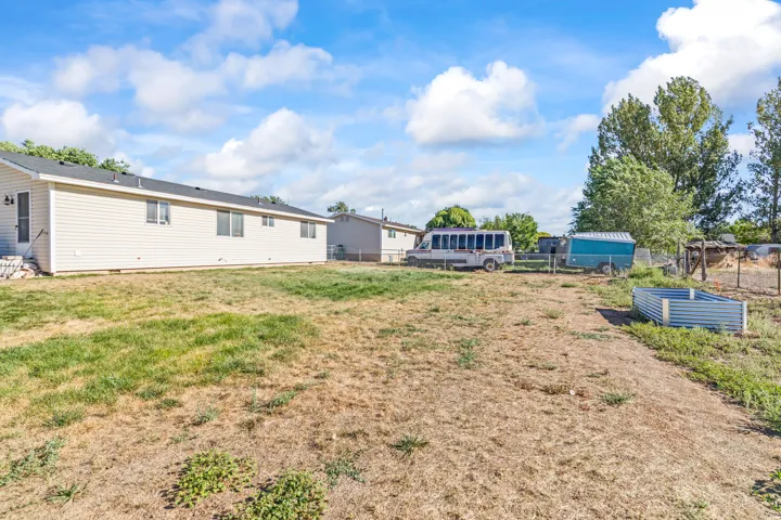 Expansive yard space with established trees and a raised garden bed