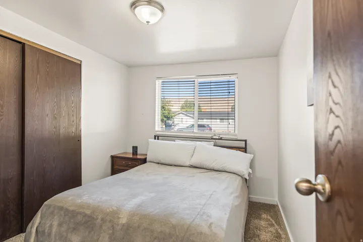 Window with horizontal blinds, wood-finish bi-fold closet doors, and neutral wall paint