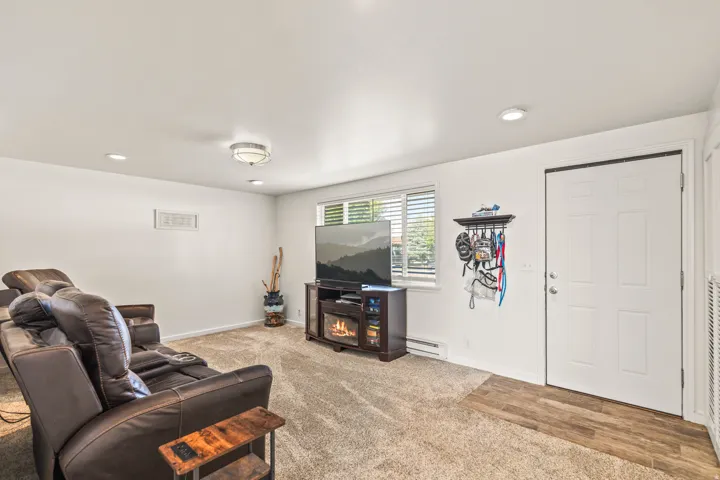 Recessed lighting, flush-mount ceiling fixture, window with horizontal blinds, wood-finish flooring, and a paneled door