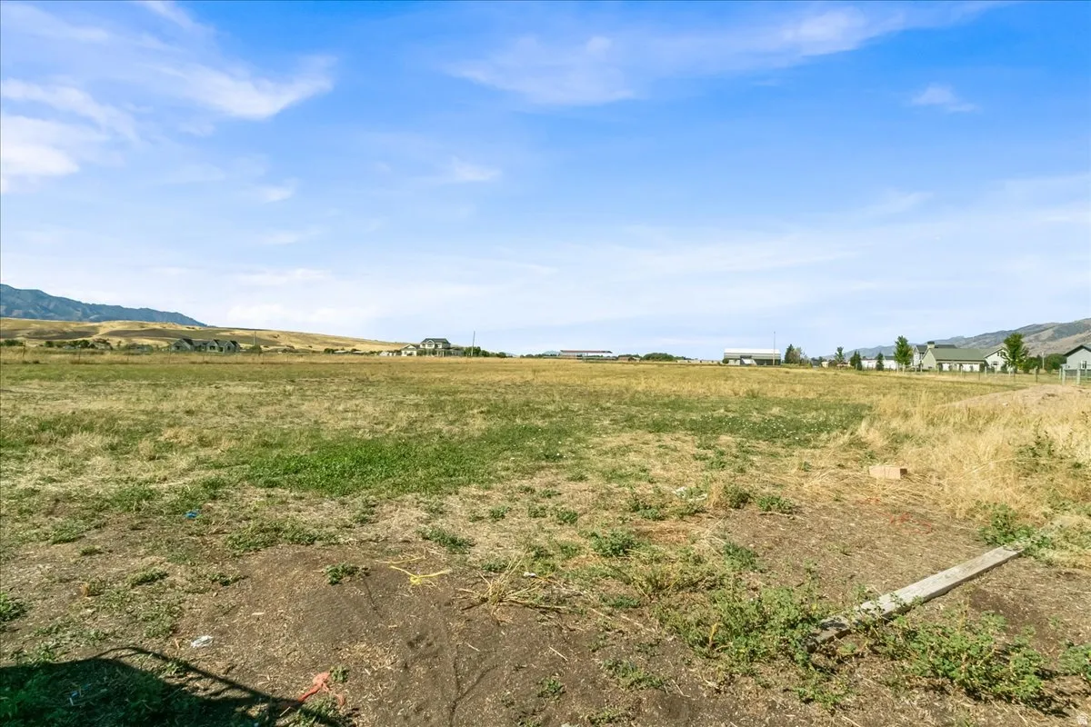 Expansive open land with surrounding distant mountain ranges and scattered residential structures