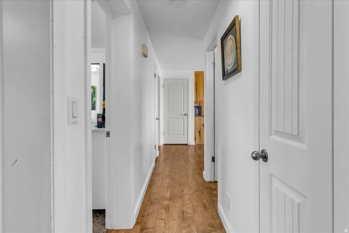 Wood-finish flooring throughout a hallway with white paneled walls and white doors