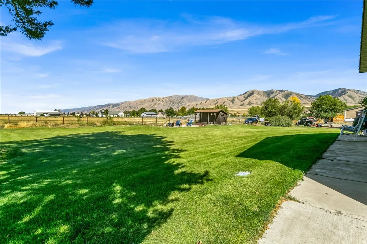 Expansive grassy lawn with a concrete patio and a wooden storage shed