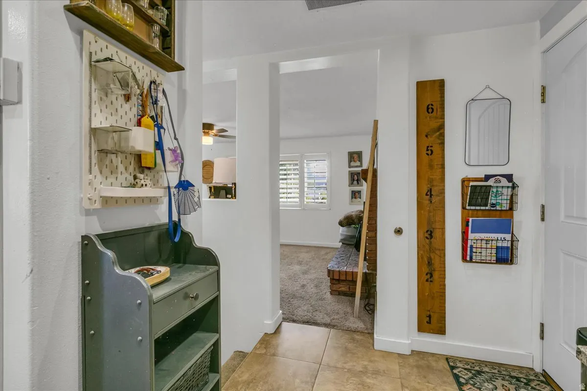 Tile flooring entryway leading to an interior space with carpet and plantation shutters