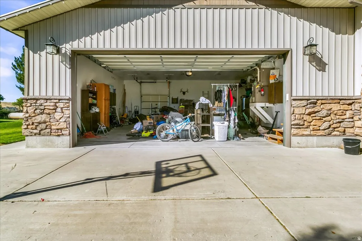 Garage with concrete driveway, stone veneer accents, vertical panel siding, and exterior wall lanterns