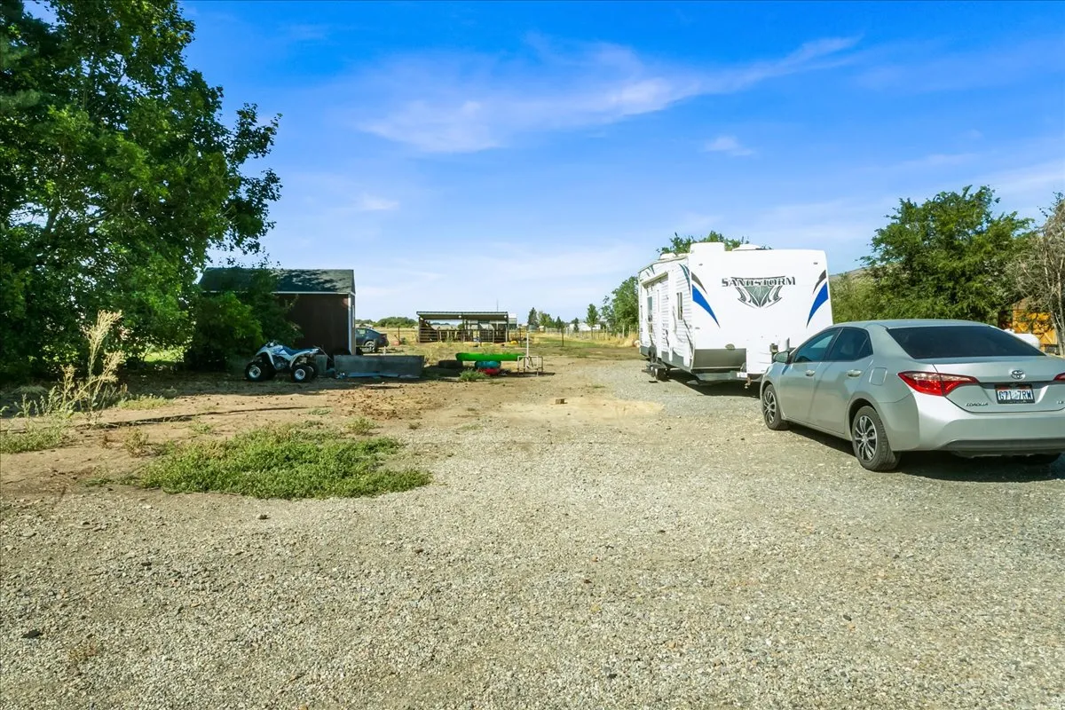 Gravel parking area with a separate storage shed and open-air structure