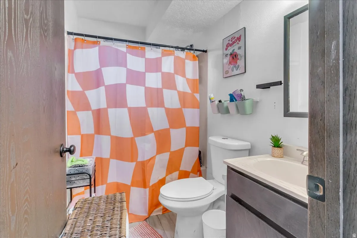 Bathroom featuring a single vanity with an integrated sink, framed mirror, and wood-finish door
