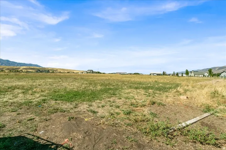 Expansive open land with surrounding distant mountain ranges and scattered residential structures