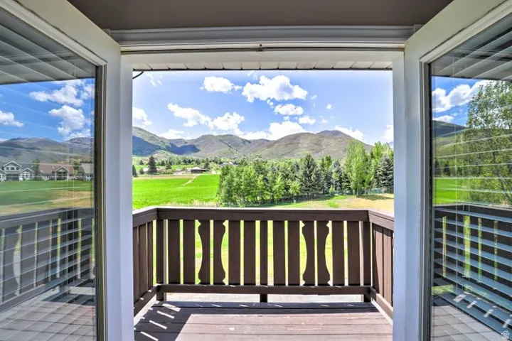 Wood-finish balcony flooring with a solid railing, offering expansive mountain scenery
