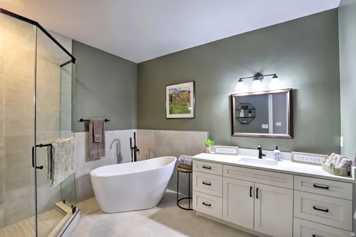 Spacious bathroom featuring a frameless glass shower enclosure, freestanding soaking tub, dual-sink vanity with white cabinetry, and matte black fixtures