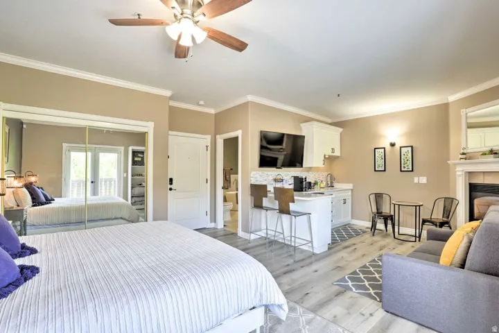 Crown molding details, wood-finish flooring, mirrored closet doors, a built-in wet bar, and a fireplace with a white mantel