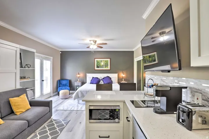 Open-concept living area with wood-finish flooring, a contemporary kitchen island, built-in shelving, and French patio doors