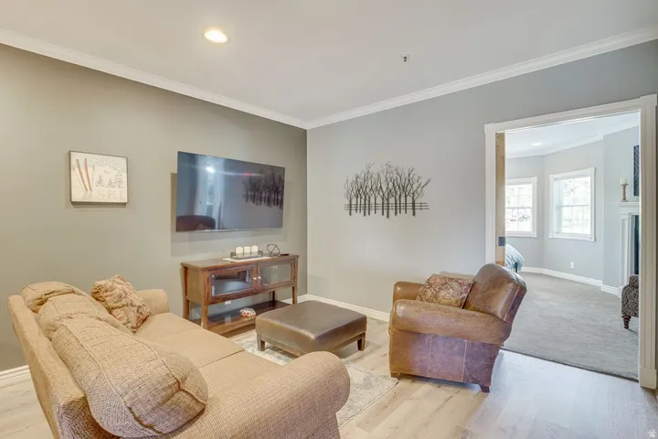 Recessed lighting, crown molding, and light wood-finish flooring