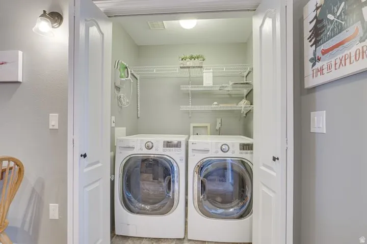 Dedicated laundry closet featuring a built-in wire shelving system, dual front-loading machines, and recessed ceiling lighting