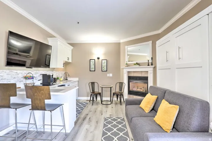 Crown molding, wood-finish flooring, built-in cabinetry, white shaker-style cabinetry, and gas fireplace with tile surround