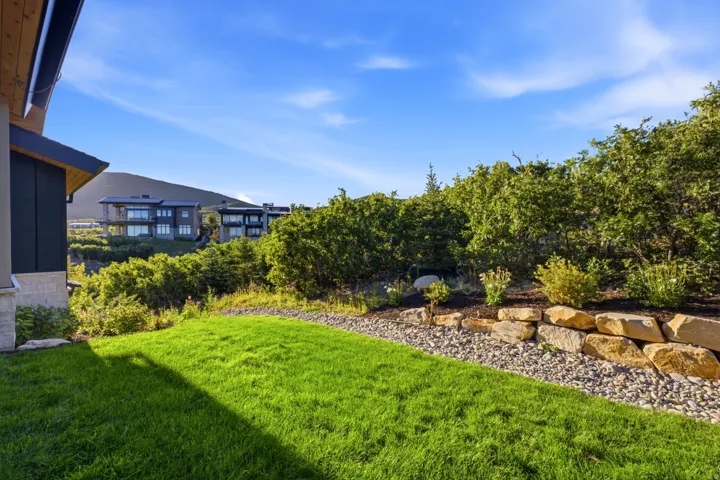 Landscaped exterior featuring a sloped lawn, natural stone retaining wall, and mature shrubbery