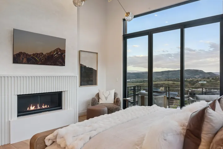 Integrated fireplace with fluted paneling, floor-to-ceiling sliding glass doors, and a transparent glass railing balcony