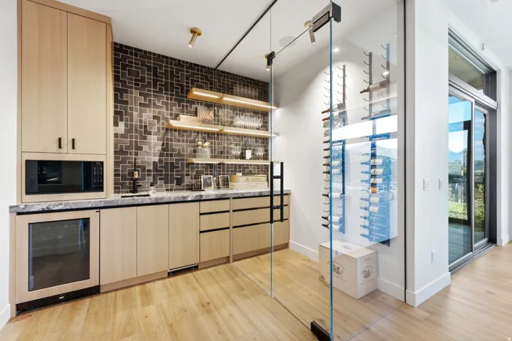 Built-in wet bar with wood-finish cabinetry, stone countertop, and microwave