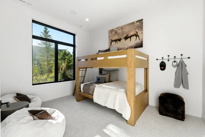 Recessed lighting, wood-finish bunk beds, broad window, light-colored carpeting, and white walls