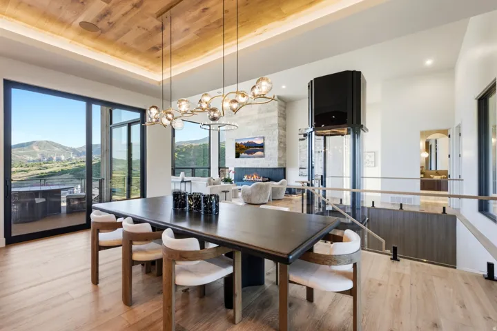 Wood-finish flooring, full-height glass sliding doors, wood-paneled ceiling, contemporary chandelier, and a built-in elevator