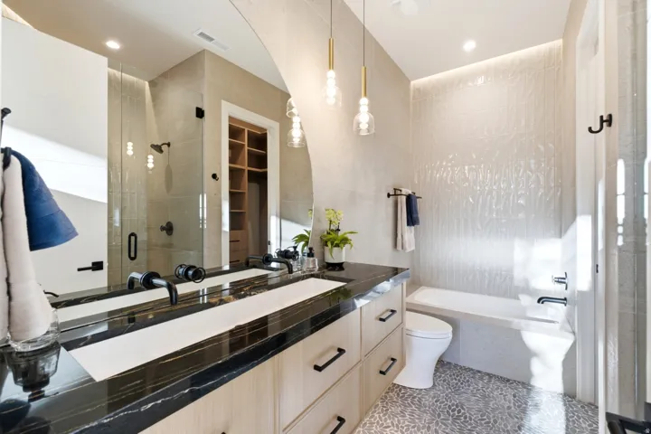 Double vanity with a dark stone countertop, integrated sinks, and matte black fixtures