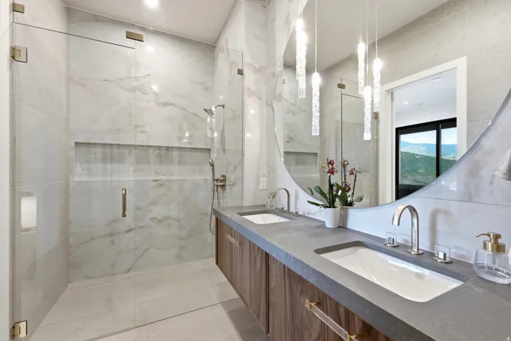 Dual vanity with wood-finish cabinetry, under-mount sinks, and a dark stone countertop