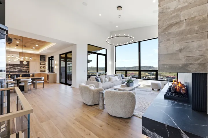 Expansive living area with high ceilings, large format windows, and wood-finish flooring