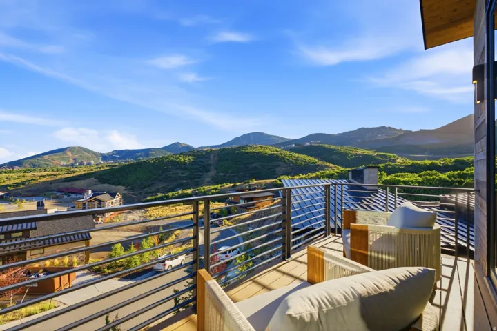 Balcony with horizontal metal railings, wood-finish decking, and mountain scenery